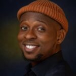 A close-up portrait of a smiling man wearing a beanie, showcasing joy and warmth.