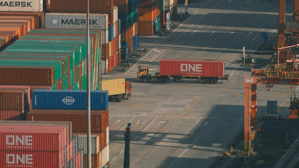 Rows of stacked shipping containers and port cranes at a busy container port