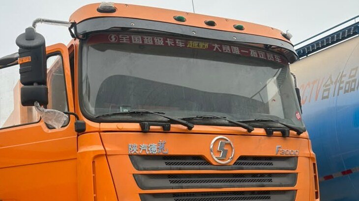 Orange Shacman heavy truck parked in a yard, ready for inspection and handover